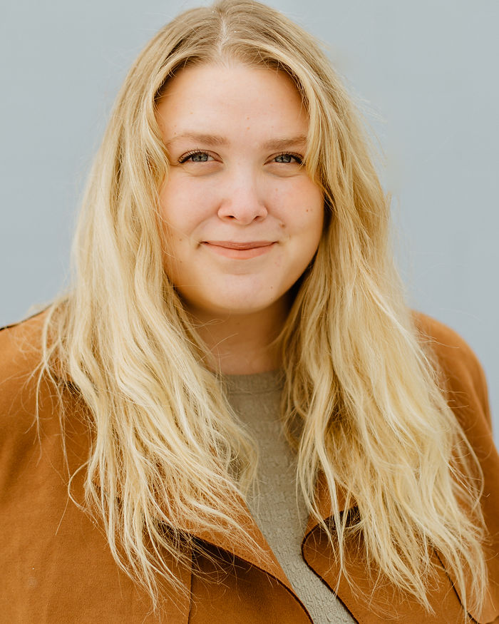 Portrait of Erin Girard smiling, with blonde hair, against a plain background.